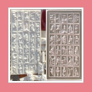 May include: A rectangular white silicone mold featuring a grid of twenty-four distinct embossed designs, including figures of people, animals, and structures. The mold is shown in two views, displaying the intricate relief patterns clearly.