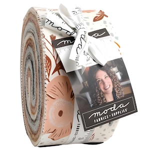 Puede incluir: Un rollo de tela con estampados florales y de hojas en tonos melocotón, marrón y crema. La tela está atada con una cinta blanca e incluye una etiqueta con el texto "moda FABRICS + SUPPLIES".