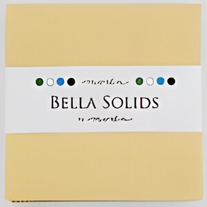 Puede incluir: Un paquete cuadrado de color amarillo claro con una banda blanca envuelta. La banda presenta el texto "BELLA SOLIDS" en una fuente estilizada, con una serie de puntos de colores encima del texto. El paquete está sobre un fondo blanco.