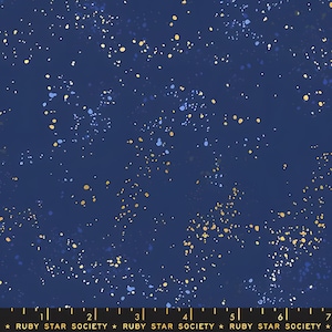 Könnte beinhalten: Ein dunkelblauer Stoff mit einem verstreuten Muster aus goldfarbenen, hellblauen und weißen farbspritzerartigen Punkten. Eine schwarze Webkante unten zeigt den wiederholten weißen Text "RUBY STAR SOCIETY" und ein Lineal bis 18 cm.