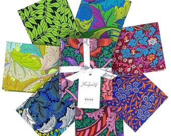 Può includere: Un set di sei quadrati di tessuto con motivi floreali e fogliari colorati. I quadrati di tessuto sono disposti in cerchio attorno a un'etichetta regalo bianca con il testo "Free Spirit" stampato su di essa.