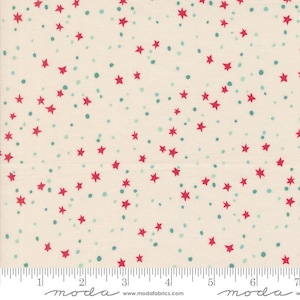 May include: Cream-colored fabric patterned with scattered red stars and small teal dots. The stars are five-pointed and evenly distributed across the fabric. A ruler is visible along the bottom edge, marked in inches.