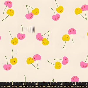 Könnte beinhalten: Cremefarbener Stoff mit einem sich wiederholenden Muster aus rosa und gelben Cartoon-Kirschen. Jede Kirsche hat ein lächelndes Gesicht und grüne Stiele. Der Text "RUBY STAR SOCIETY" befindet sich am unteren Bildrand.