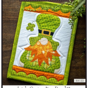 May include: A green and orange Irish gnome mug rug kit. The kit includes instructions, precut fused appliqué, and all of the fabric to complete the mug rug. Finished size: 7 inches by 10 inches. The Whole Country Caboodle. BX133. Leanne Anderson 2021.