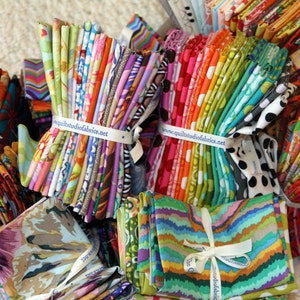 May include: A collection of colorful fabric scraps bundled together with a white ribbon and a label that reads "www.quiltstudiofabrics.net".