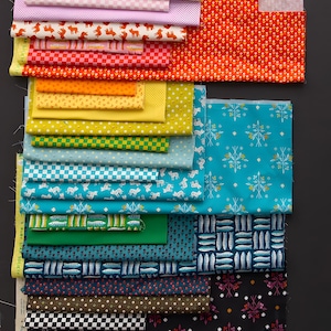 Puede incluir: Una colección de muestras de tela coloridas con varios patrones. Los diseños incluyen estampados florales, geométricos y de animales en tonos de rosa, naranja, amarillo, verde y azul. Las telas están apiladas sobre una superficie oscura.