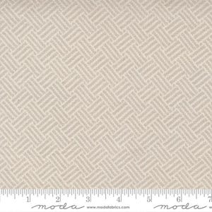 May include: A close-up of a beige fabric with a subtle herringbone pattern. The fabric is textured and has a slightly rough feel. The fabric is measured in inches on a ruler.