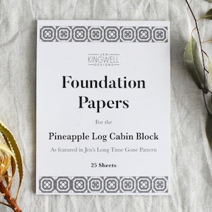 May include: A white sheet of paper with black text that reads "Foundation Papers for the Pineapple Log Cabin Block As featured in Jen's Long Time Gone Pattern 25 Sheets". The paper has a black and white geometric border.
