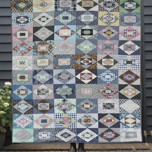 May include: A quilt pattern called "Wensleydale" by Jen Kingwell, featuring a geometric design with a variety of colorful fabrics. The quilt is displayed in front of a gray wooden door. The text "Acrylic Templates Only" and "Pattern featured in Quilt Recipes Book" is also visible.