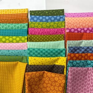 May include: A collection of folded fabric squares featuring a variety of geometric, floral, and star patterns in a vibrant palette of yellow, orange, green, blue, pink, and purple. Each piece displays a distinct repeating print on cotton material.