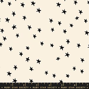 以下が含まれることがあります： クリーム色の生地に、手描き風の小さな黒い星が散りばめられた繰り返し模様が施されています。下部にある黒い定規にはインチ単位の目盛りが表示されており、Ruby Star Societyという文字が繰り返しプリントされています。