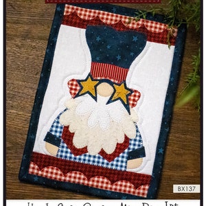 May include: A red, white, and blue Uncle Sam gnome mug rug kit. The kit includes instructions, precut fused appliqué, and all the fabric needed to complete the mug rug. The finished size is 7 inches by 10 inches.