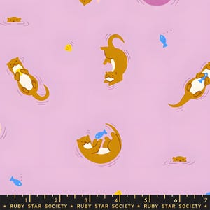 Puede incluir: Una tela de color morado claro con un patrón repetitivo de nutrias marrones con vientres blancos, algunas nadando y otras sosteniendo peces azules. Una regla negra en la parte inferior muestra 18 cm, con el texto Ruby Star Society impreso.