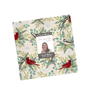 May include: A stack of fabric squares with a winter theme. The fabric features red cardinals, small birds, and green foliage on a cream background. A tag with the text "When Snow Falls" is attached.