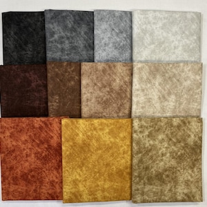 May include: A collection of square fabric swatches in various colors, including black, gray, brown, and gold. The fabric has a textured, velvet-like appearance, with subtle variations in color and tone across each swatch.
