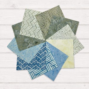 May include: A collection of ten square fabric swatches arranged in a circular fan pattern. The fabric pieces feature various batik-style patterns including geometric triangles, zigzags, and parallel lines in shades of blue, green, and cream.