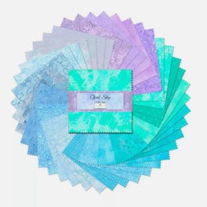 May include: A pack of 24 fabric squares in shades of blue and purple. The squares feature a variety of patterns, including tie-dye, bubbles, and floral designs. The pack is labeled "Opal Sky 5-Inch Squares".