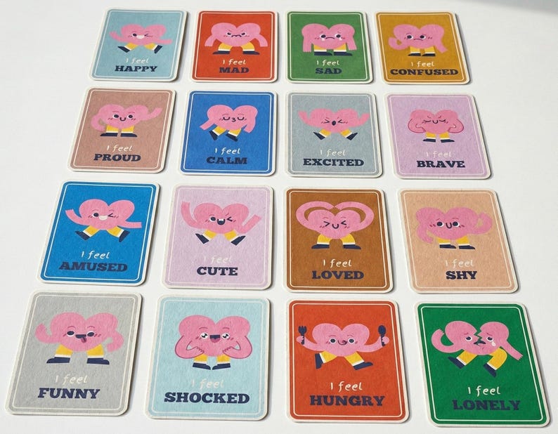 May include: A collection of colorful emotion cards. Each card features a pink heart character with arms and legs, expressing different feelings. The cards have text such as "I feel happy," "I feel sad," and "I feel loved."