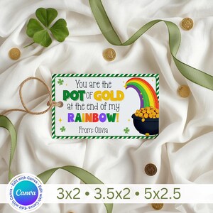 Puede incluir: Una etiqueta de regalo del Día de San Patricio con el texto "You are the POT OF GOLD at the end of my RAINBOW!" y "From: Olivia". La etiqueta presenta un arcoíris, una olla de oro y tréboles. Monedas de oro y cinta verde están esparcidas alrededor de la etiqueta.
