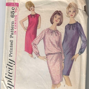 May include: Vintage Simplicity sewing pattern number 5529 for a dress with a tie neckline. The pattern is for sizes 12 and bust 32. The pattern shows three different styles of the dress, one in pink, one in a pink and white gingham, and one in purple.