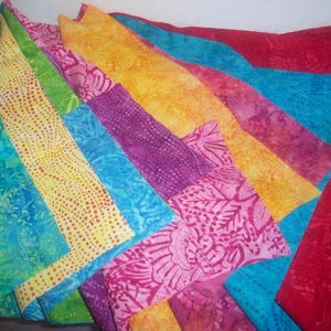 May include: A collection of colorful fabric squares with various patterns, including floral, geometric, and abstract designs. The fabrics are arranged in a layered, overlapping pattern, creating a vibrant and textured display.