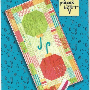 Könnte beinhalten: Ein Quiltmuster für einen Tischläufer mit einem farbenfrohen Regenschirm-Design. Das Muster trägt den Titel "#350 Table Attire (Charm Pack pattern)" und stammt aus der Kollektion "Pieces from my Heart".