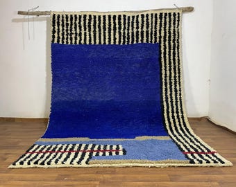 Alfombra marroquí hecha a mano a medida con centro azul real y borde a rayas negras y crema.