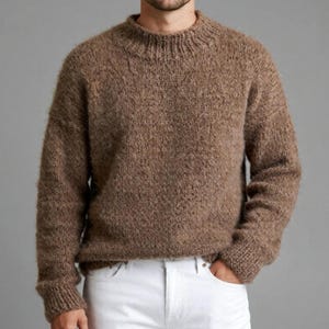 May include: A brown, textured knitted jumper with a crew neck and long sleeves. The jumper is paired with white denim jeans. The style is casual and comfortable, suitable for cooler weather.