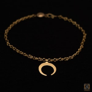 Op de afbeelding: Een gouden ketting met een halve maan hanger.