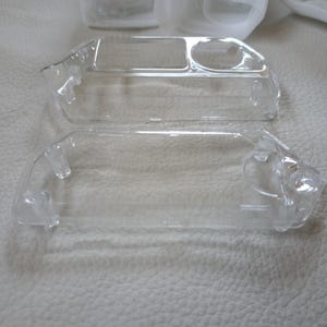 May include: Two clear plastic cases for electronics. The cases are empty and have a rectangular shape.