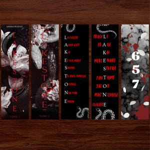 Peut inclure: Cinq marque-pages avec un design sombre et gothique. Ils présentent des illustrations de serpents et de fleurs, avec du texte blanc et rouge. Les marque-pages sont posés sur un fond en bois sombre.