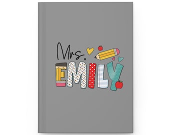 May include: Gray notebook with the text "Mrs. Emily" in colorful letters with a pencil, apple, and hearts around the text.