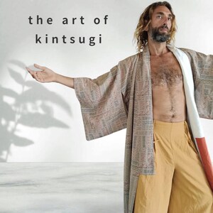 Puede incluir: Una persona lleva una larga túnica estampada con una faja blanca. La túnica está abierta, dejando ver un pantalón amarillo. La persona tiene el pelo largo y castaño y barba. El texto "the art of kintsugi" está escrito en letras negras sobre un fondo blanco.
