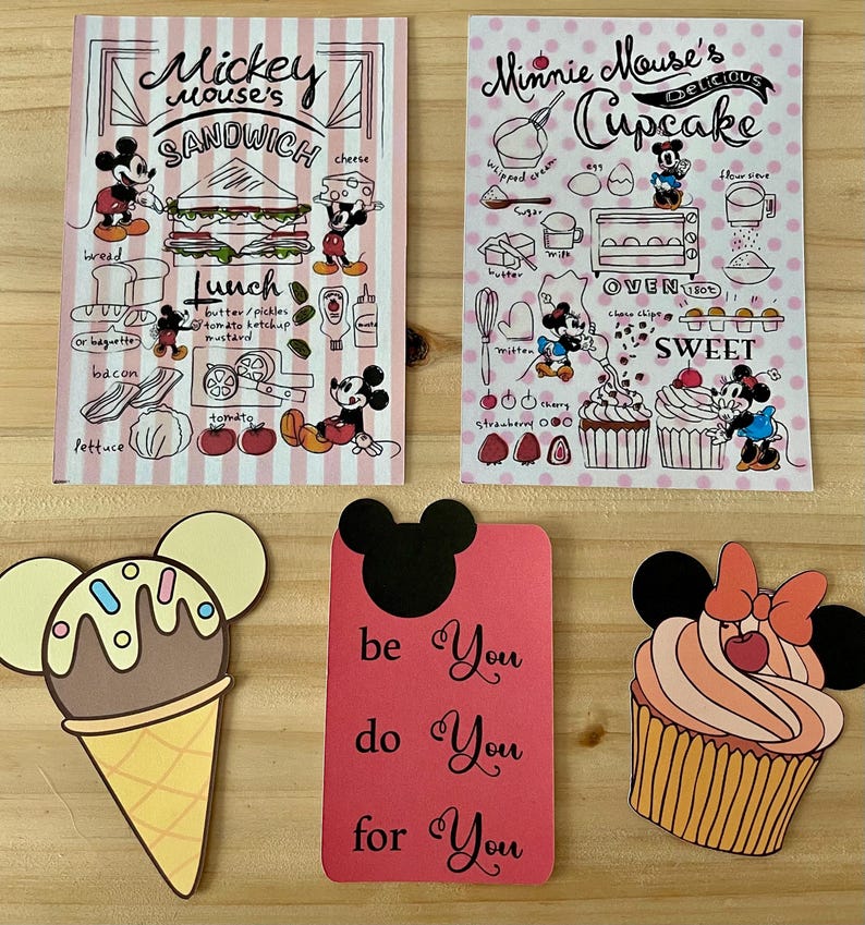 May include: A collection of Disney-themed paper cutouts and illustrations. Includes a Mickey Mouse sandwich design, a Minnie Mouse cupcake recipe, an ice cream cone, a card with the text "be You do You for You", and a cupcake.