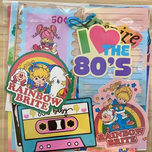 May include: A collection of colorful 1980s-themed stickers and ephemera. Includes Rainbow Brite and cassette tape designs, along with the phrase "I love the 80's". The stickers feature vibrant colors and cartoon characters, perfect for nostalgic decor.