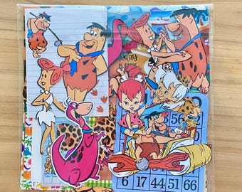 Peut inclure: Une collection de découpes et d'images colorées des personnages des Pierrafeu. Les images incluent Fred, Wilma, Barney, Betty, et Dino. Les images sont sur divers fonds, dont du papier ligné et une carte de bingo.