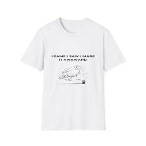 May include: White t-shirt with the text "I came. I saw. I made it awkward." and a black and white cartoon illustration of a stick figure tripping. The shirt is a casual wear item.