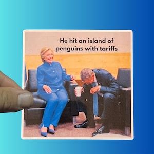 May include: A square sticker featuring a humorous image of two people in suits. The text reads, "He hit an island of penguins with tariffs." One person is smiling, the other is bent over, holding a coffee cup.
