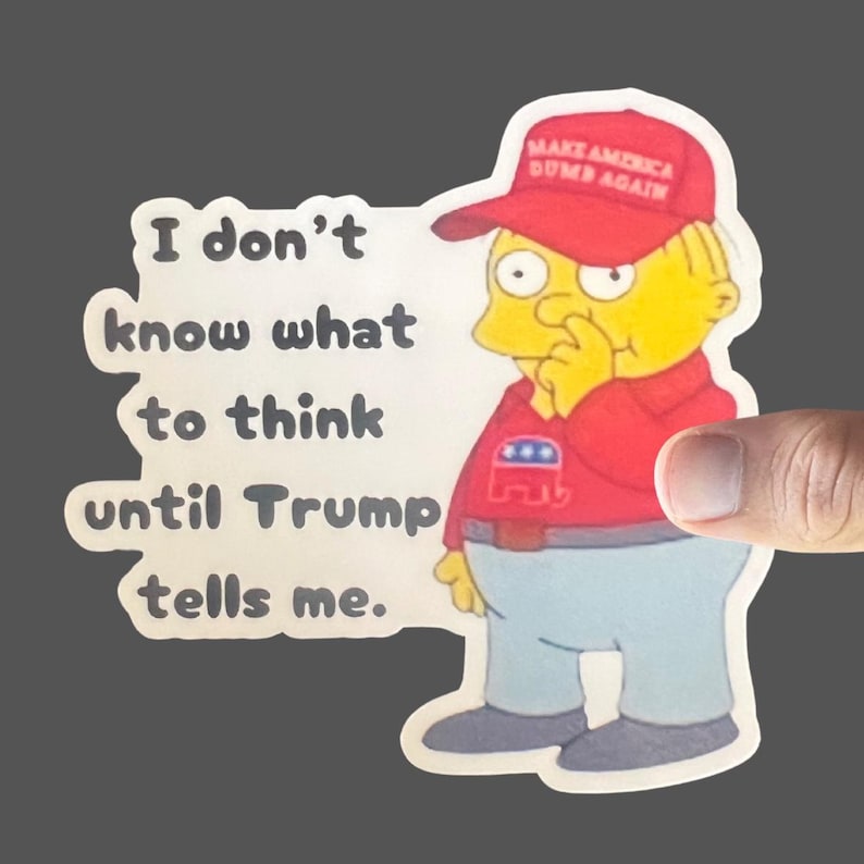 May include: A sticker featuring a cartoon character with yellow skin and a red hat that says "Make America Dumb Again". The character is wearing a red shirt with a blue elephant logo and blue jeans. The sticker has the text "I don't know what to think until Trump tells me."