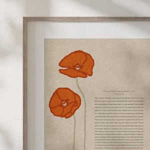 May include: Framed art print featuring two orange poppy flowers with green stems against a beige background. The artwork is in a wooden frame. The print includes text in a script font.