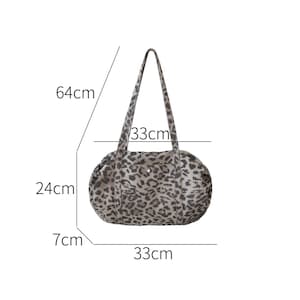 Puede incluir: Un bolso tote con estampado de leopardo de forma redondeada. El bolso mide 33 cm de largo, 24 cm de alto y 7 cm de ancho. Las asas se extienden 64 cm desde la parte superior del bolso. El bolso tiene una paleta de colores neutros de negro, gris y beige.