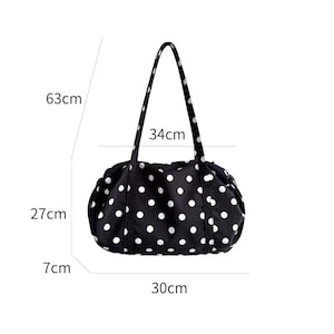 Puede incluir: Bolso tote negro con lunares blancos. El bolso mide 30 cm de largo, 27 cm de alto y 7 cm de profundidad, con una altura de asa de 63 cm y un ancho de asa de 34 cm. El bolso tiene dos asas negras.