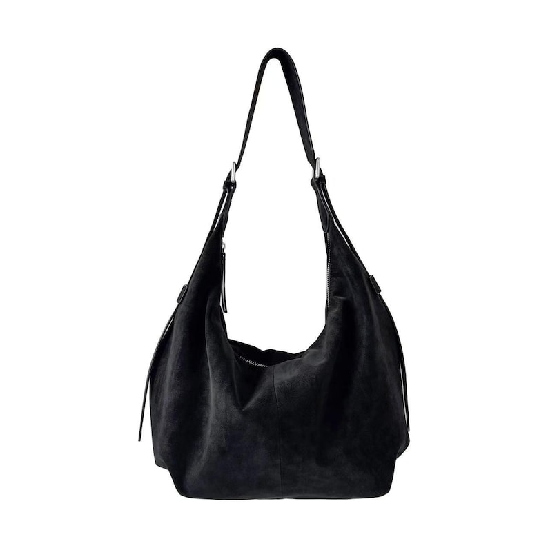 May include: A black suede shoulder bag with a single long strap. The bag has a curved shape and a zipper closure. The bag is approximately 15 inches wide and 12 inches tall.