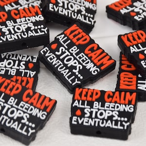 Puede incluir: Varios abalorios de silicona negros y rojos con el texto "Keep Calm All Bleeding Stops... Eventually".