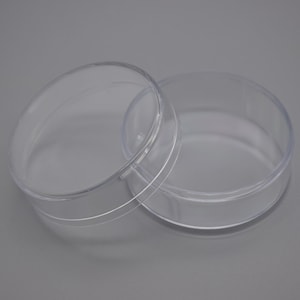 May include: Two clear, round, plastic petri dishes. One dish is open, revealing the interior. The dishes are made of transparent plastic and are designed for laboratory use. The background is a solid grey.