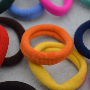 May include: Assortment of colorful hair ties in various shades of blue, red, orange, yellow, pink, green, and brown. The hair ties are made of soft, stretchy fabric and are perfect for holding back hair.
