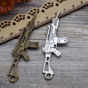 May include: Two metal toy guns, one silver and one bronze, on a wooden surface. The guns are detailed and have a realistic look.