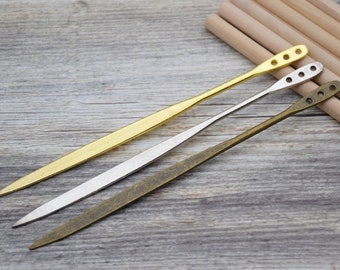 Può includere: Tre strumenti in metallo con finiture diverse: oro, argento e bronzo. Ogni strumento ha un'estremità appuntita e un manico arrotondato con dei fori.
