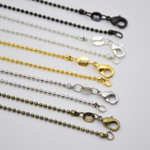 May include: Assortment of ball chain necklaces in silver, gold, and bronze finishes. Each chain features a lobster clasp closure.