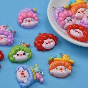 Puede incluir: Surtido de dijes coloridos con temática de payaso con caras y detalles pintados. Los dijes son de plástico y tienen un agujero para sujetarlos a joyas u otras manualidades.